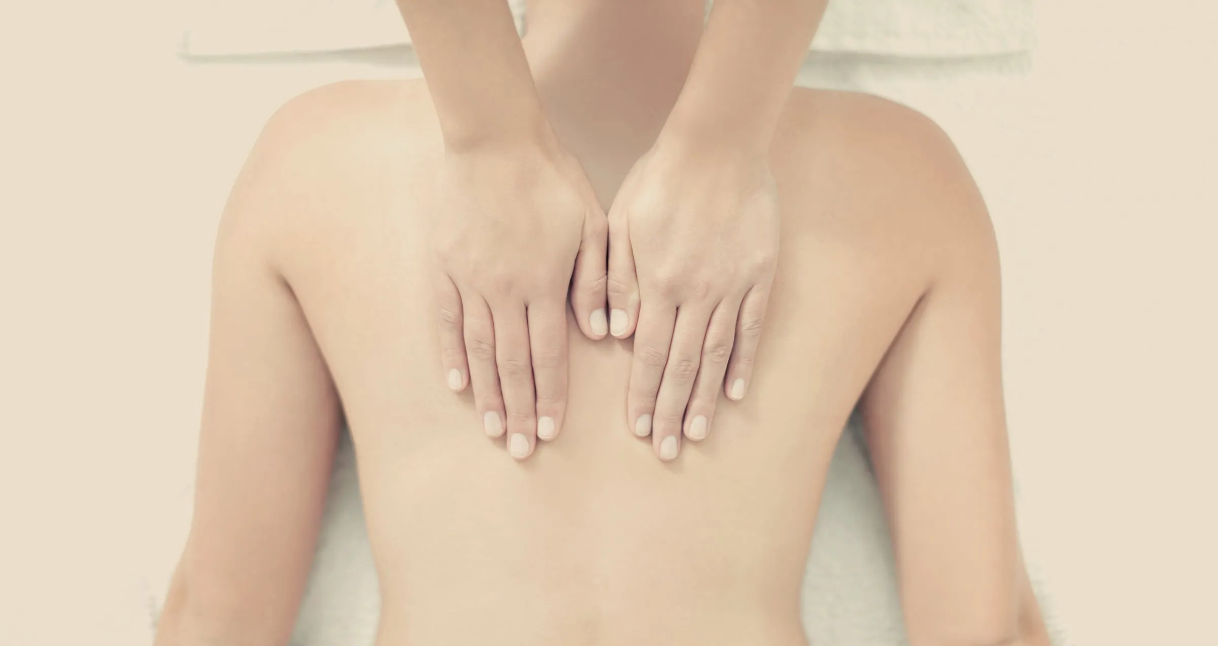 Gentle lymphatic drainage massage strokes on a client’s upper back at The Freeport House Spa